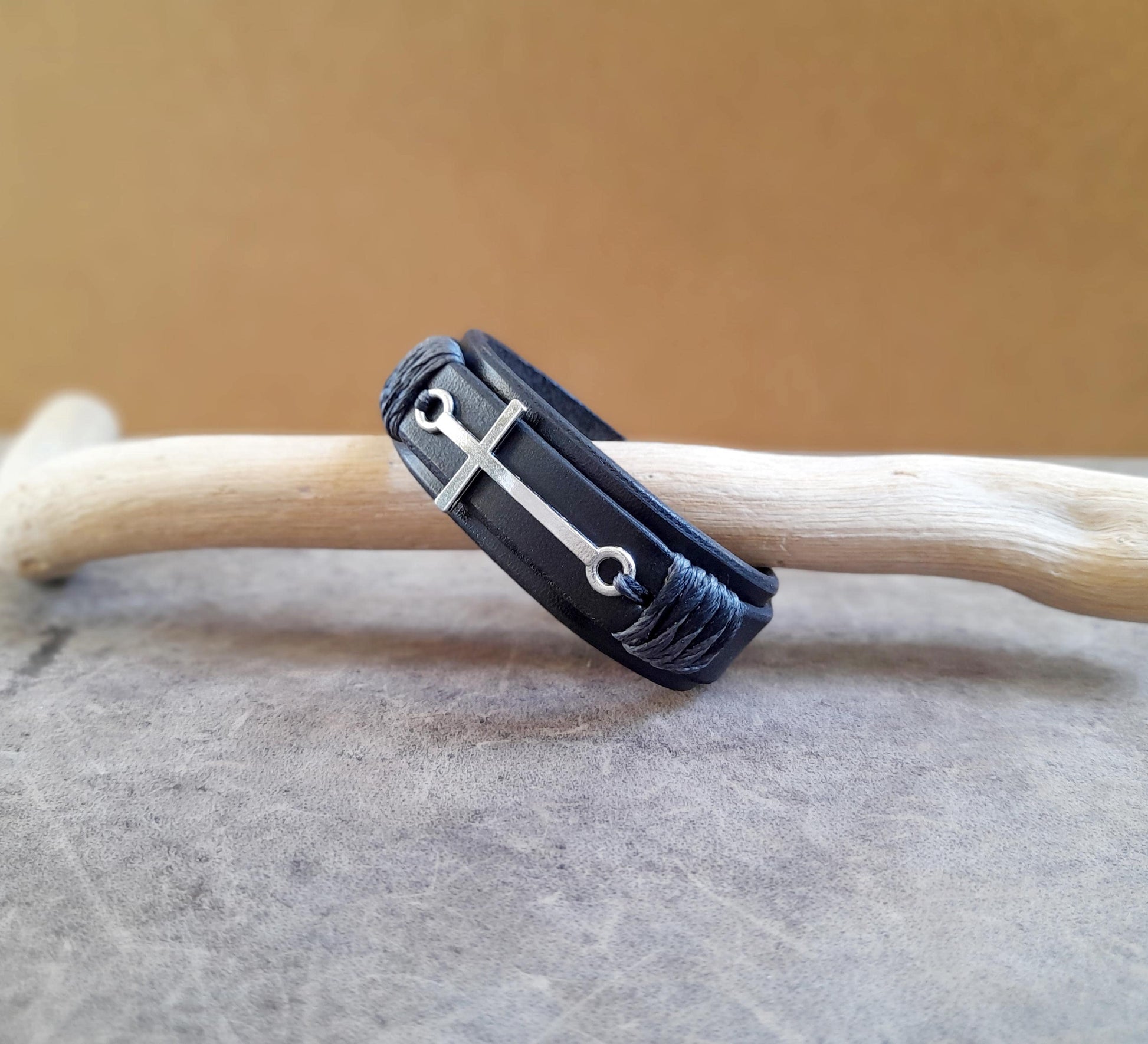 The Steadfast Spirit Cross Bracelet, all-black version, side view (other angle). Features a large horizontal stainless steel silver cross on a dual-layered black full-grain leather band.