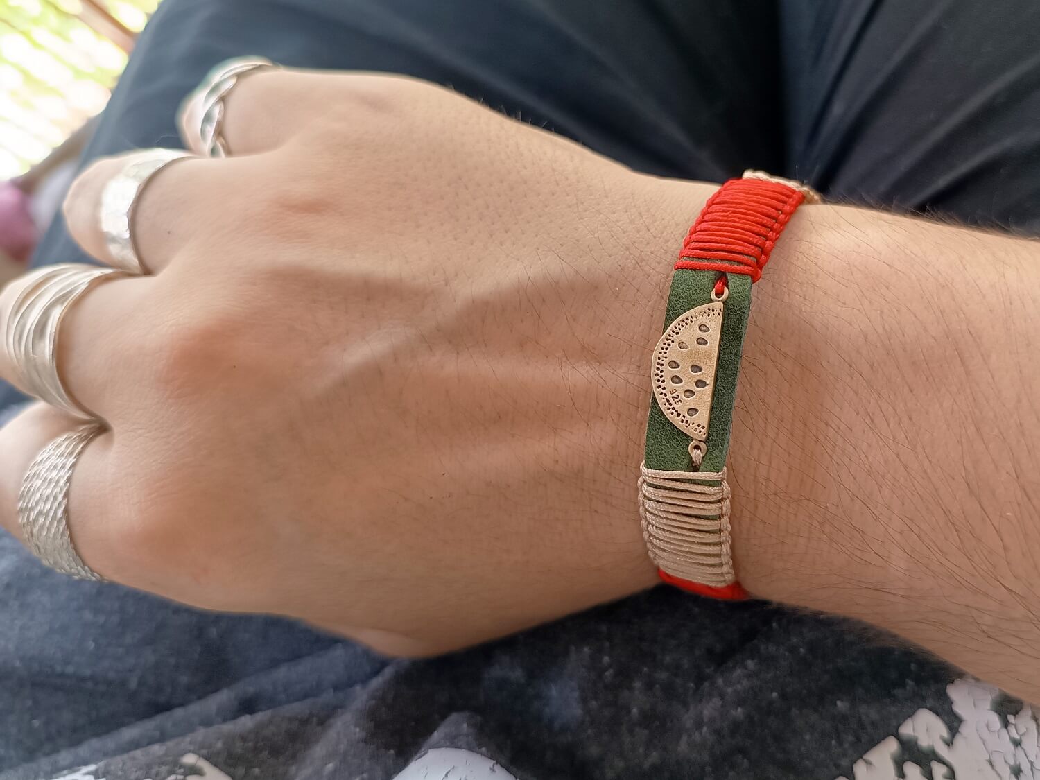 The Sweet Abundance Watermelon Bracelet worn on a wrist, showcasing its vibrant design, deep green leather, and symbolic watermelon pendant. Handmade by Lucky Seven Leather's Soulful Echoes Collection.