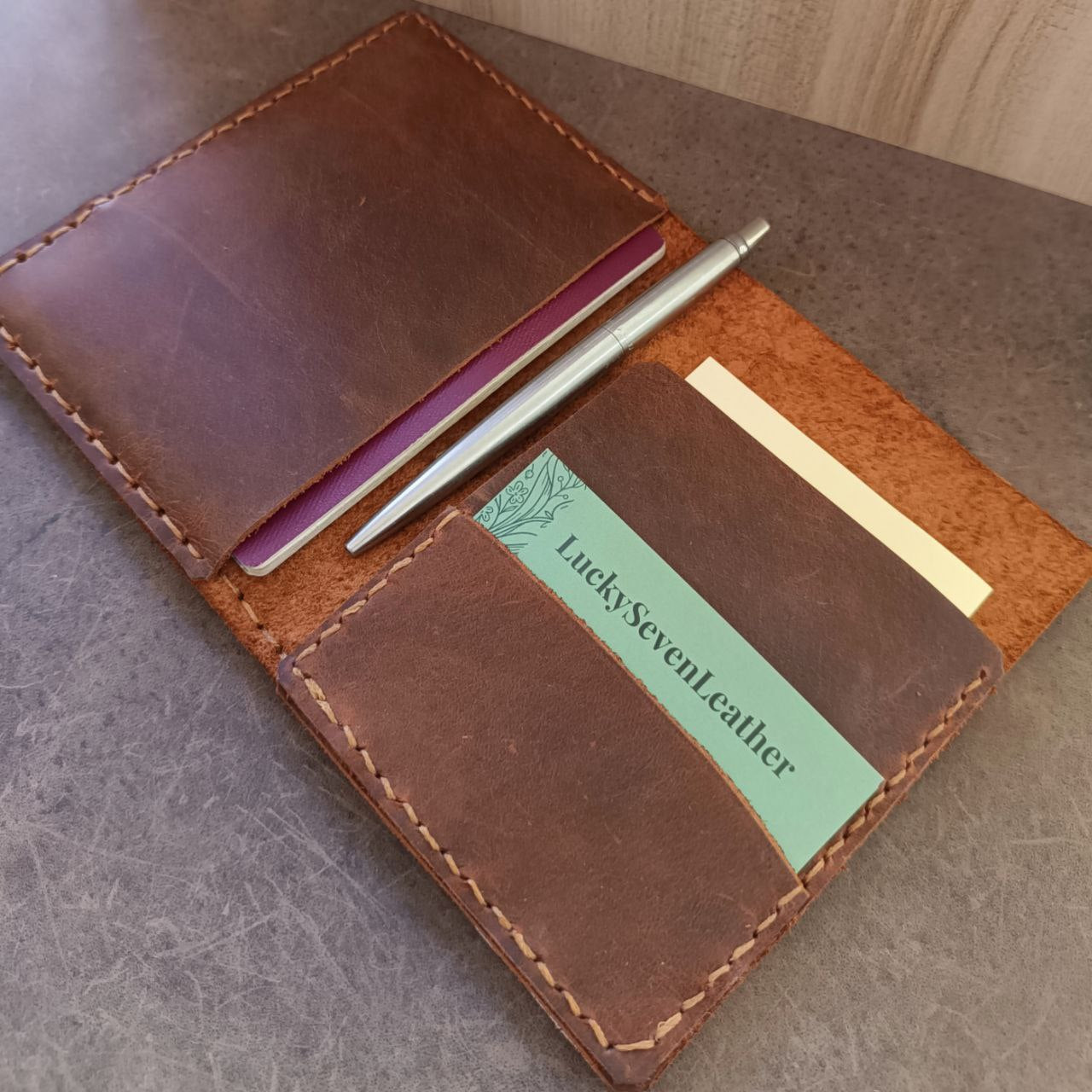 The Wanderer's Journal leather passport case, open to reveal a passport and notebook pocket, and card slot. Made from soft Crazy Horse leather.