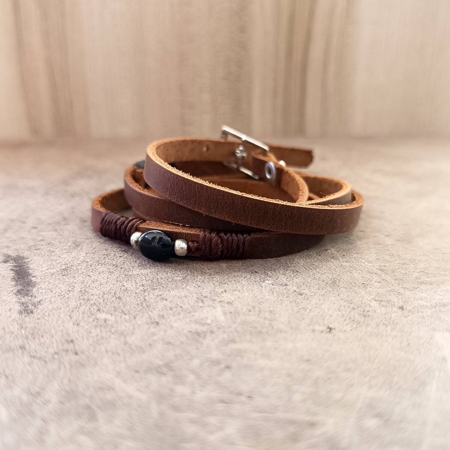 Detailed close-up of the small Black Tourmaline stone with silver accent on The Wanderer's Wrap, highlighting its texture and the rich dark brown Crazy Horse leather.