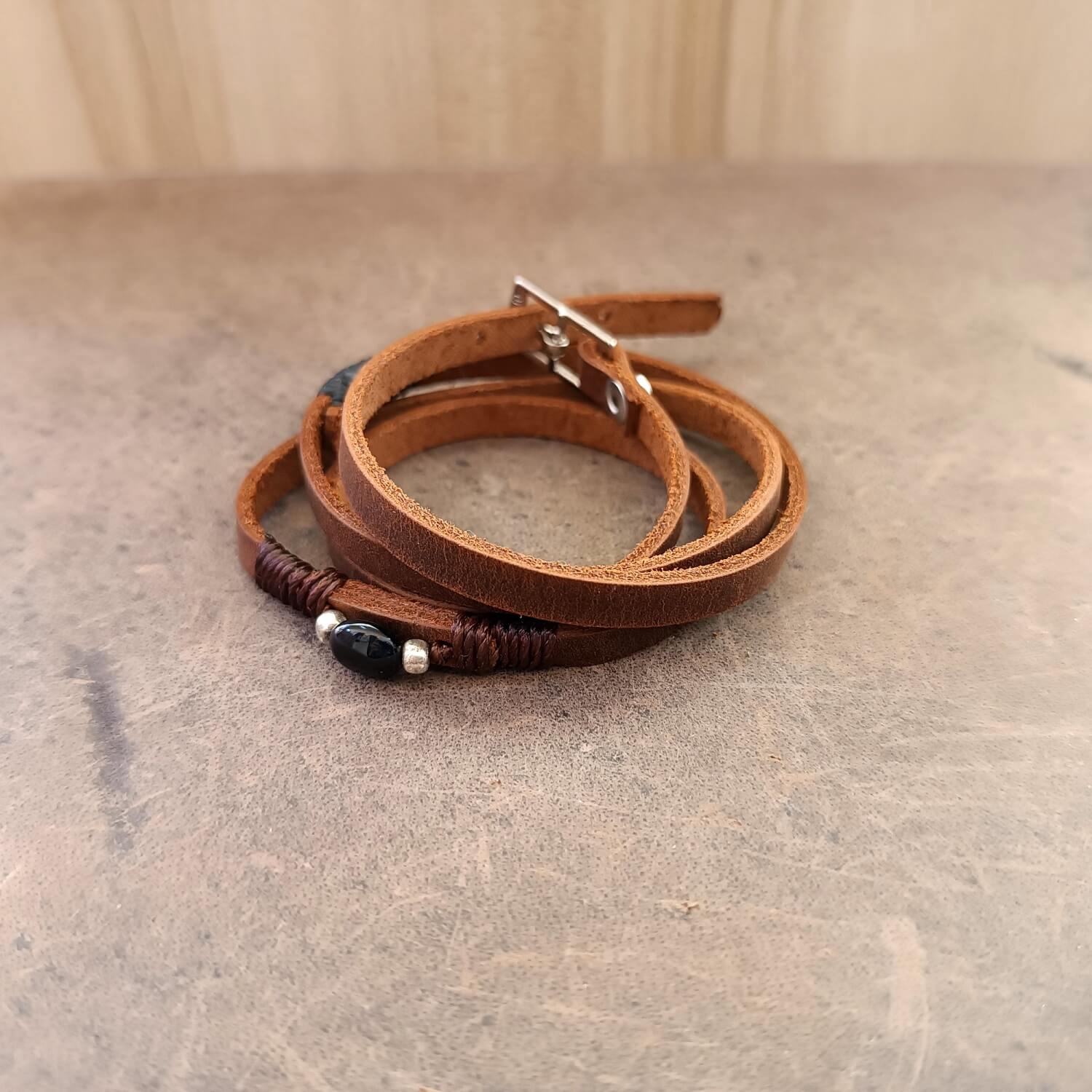 The Wanderer's Wrap shown as a four-wrap bracelet, showcasing its multi-layered look, dark brown Crazy Horse leather, and the Black Tourmaline stone.