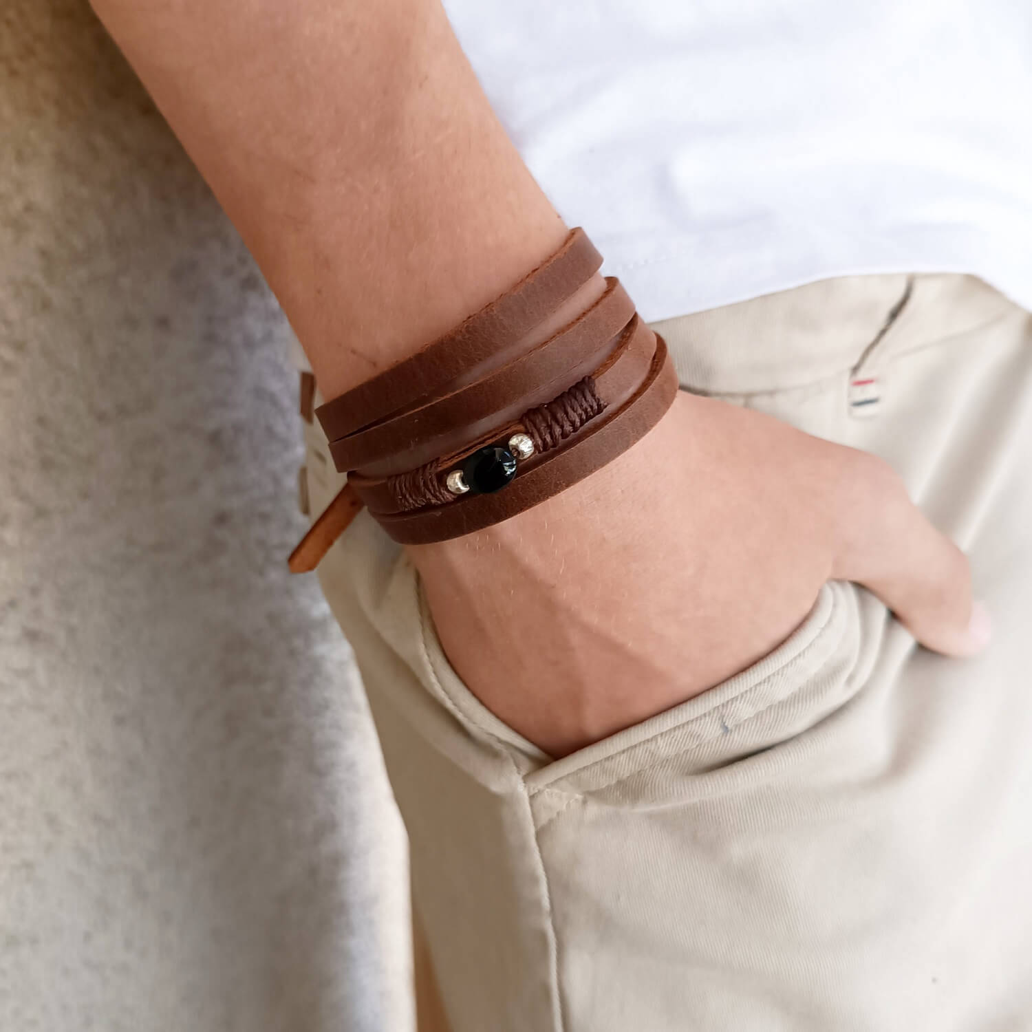 The Wanderer's Wrap worn as a four-wrap bracelet on a wrist, showcasing its multi-layered look, dark brown Crazy Horse leather, and the Black Tourmaline stone.