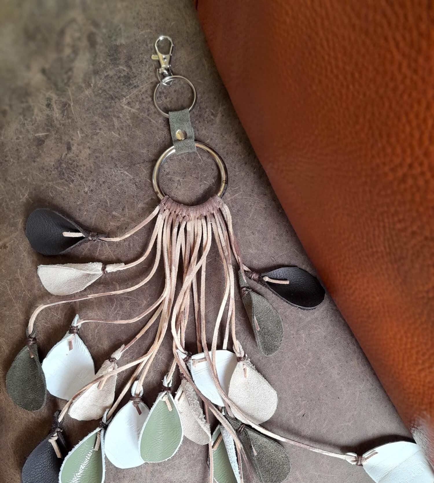 Decorative keychain with tassels and leaf-like pendants on a textured surface