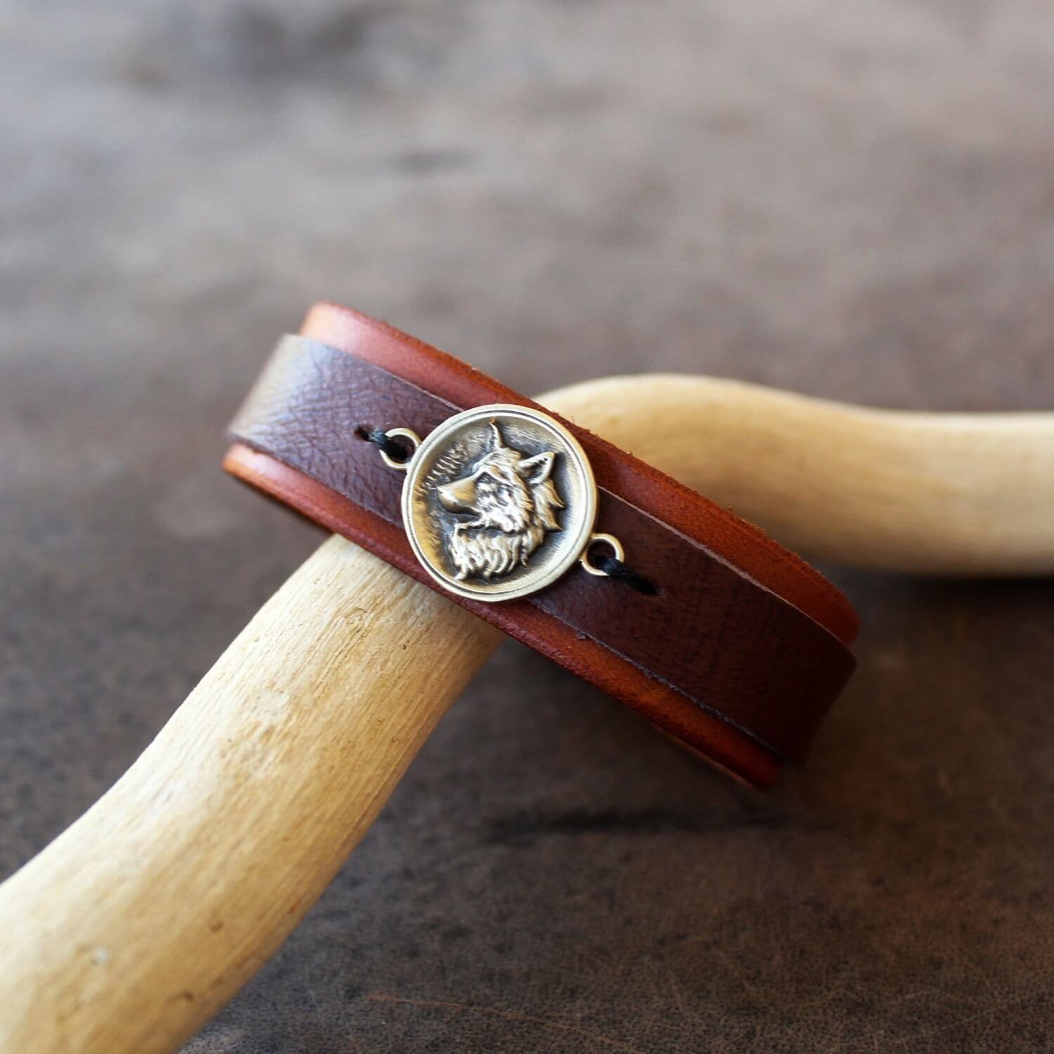 Front view: White Wolf leather bracelet in all brown full grain leather with oxidized brass wolf pendant