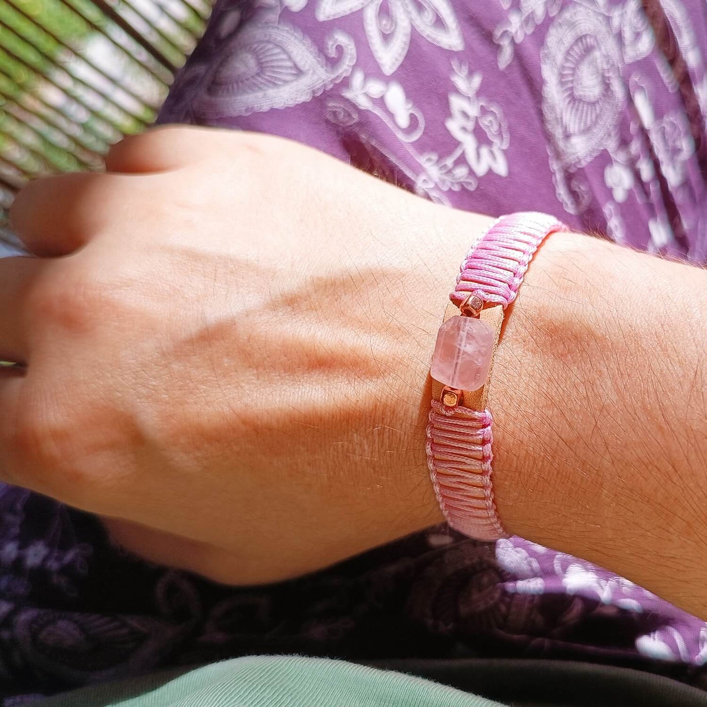 Close-up of a wrist wearing a pink beaded bracelet with a floral outfit
