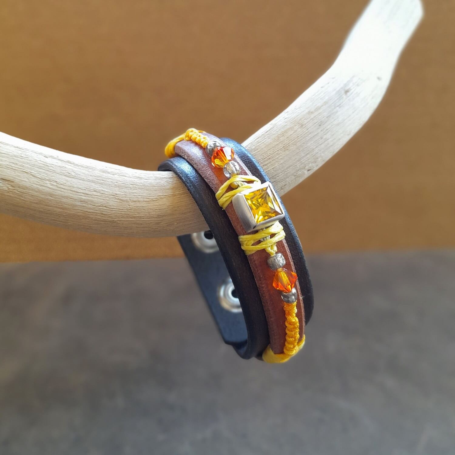 Close-up showing the two layers of dark brown and brown leather, the braided yolk yellow macramé cord, and the bright orange crystal and silver beads on the Yellow Zirconia Bracelet.