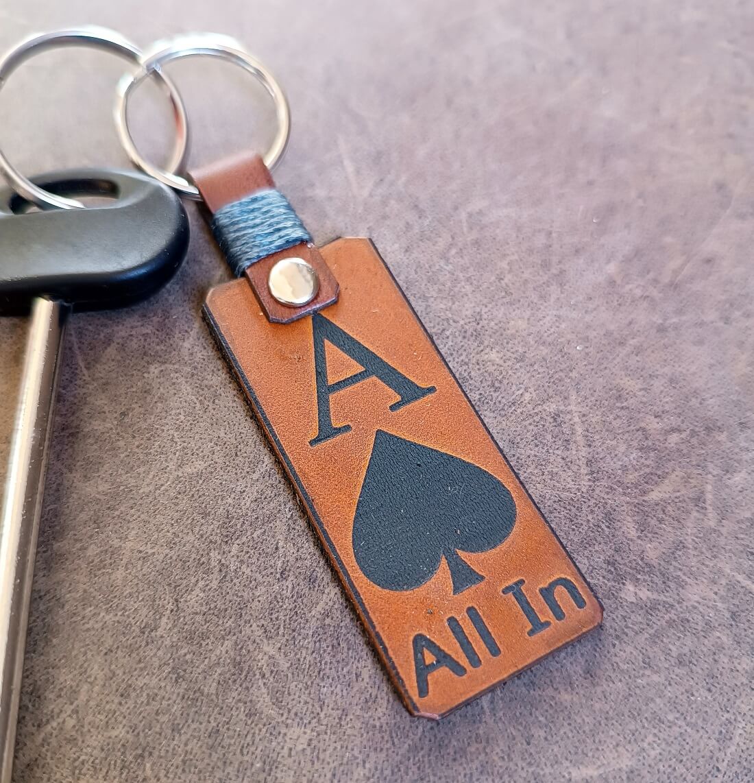 Leather keychain with 'All In' and Ace of spades design clipped on a key
