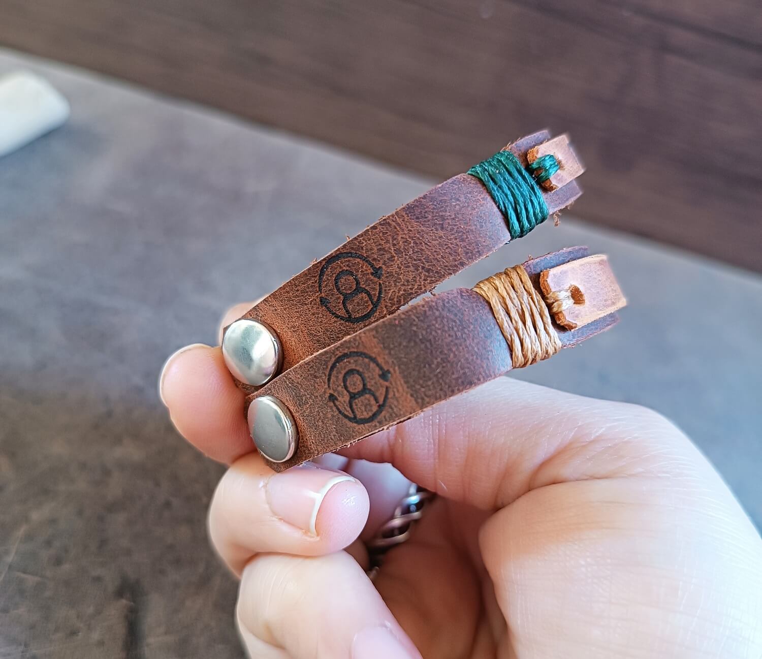 Brown leather bracelet with metal clasps held by a hand, showing the respawn engraved icons.