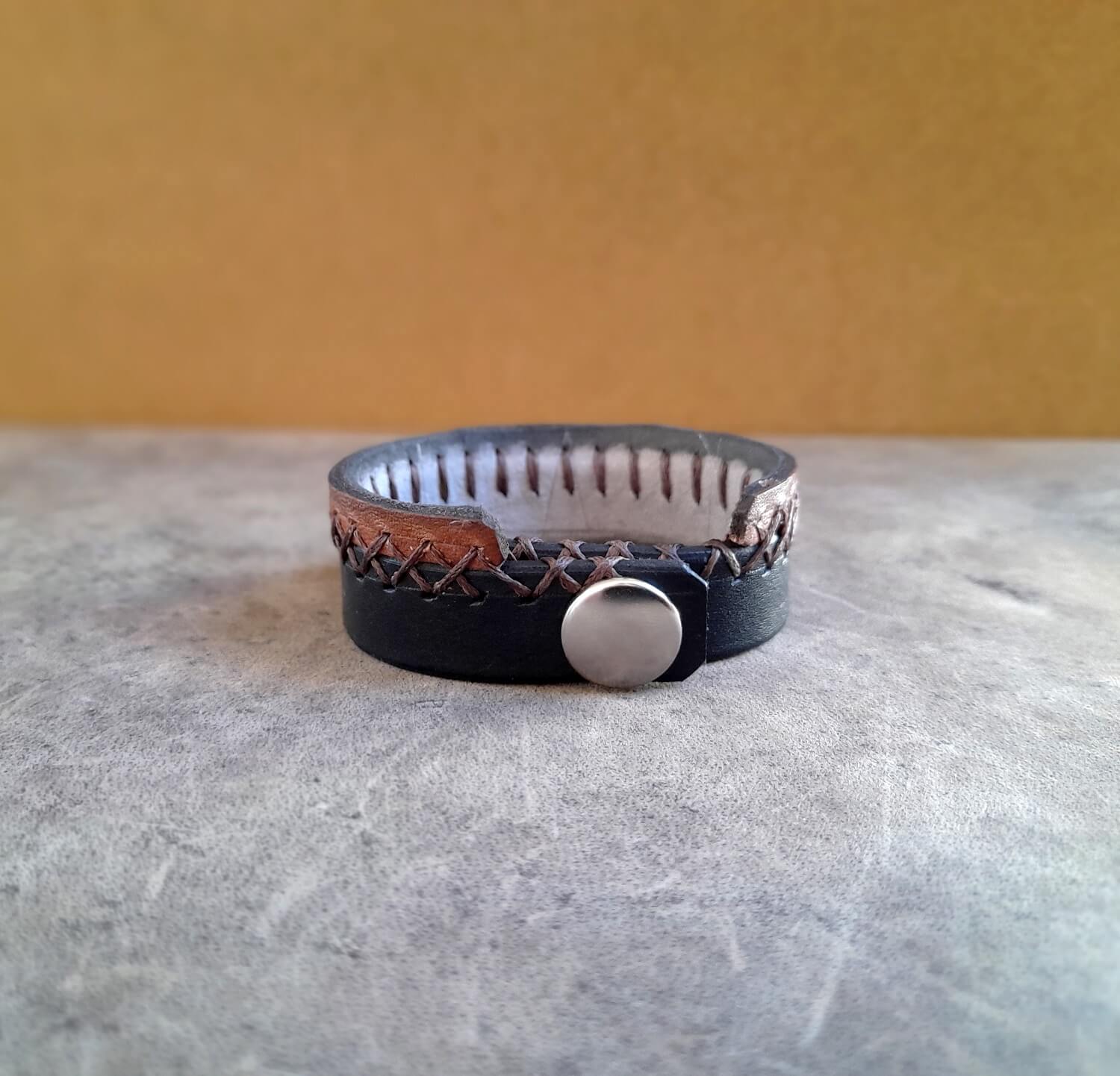 Leather bracelet with metal button on a textured surface