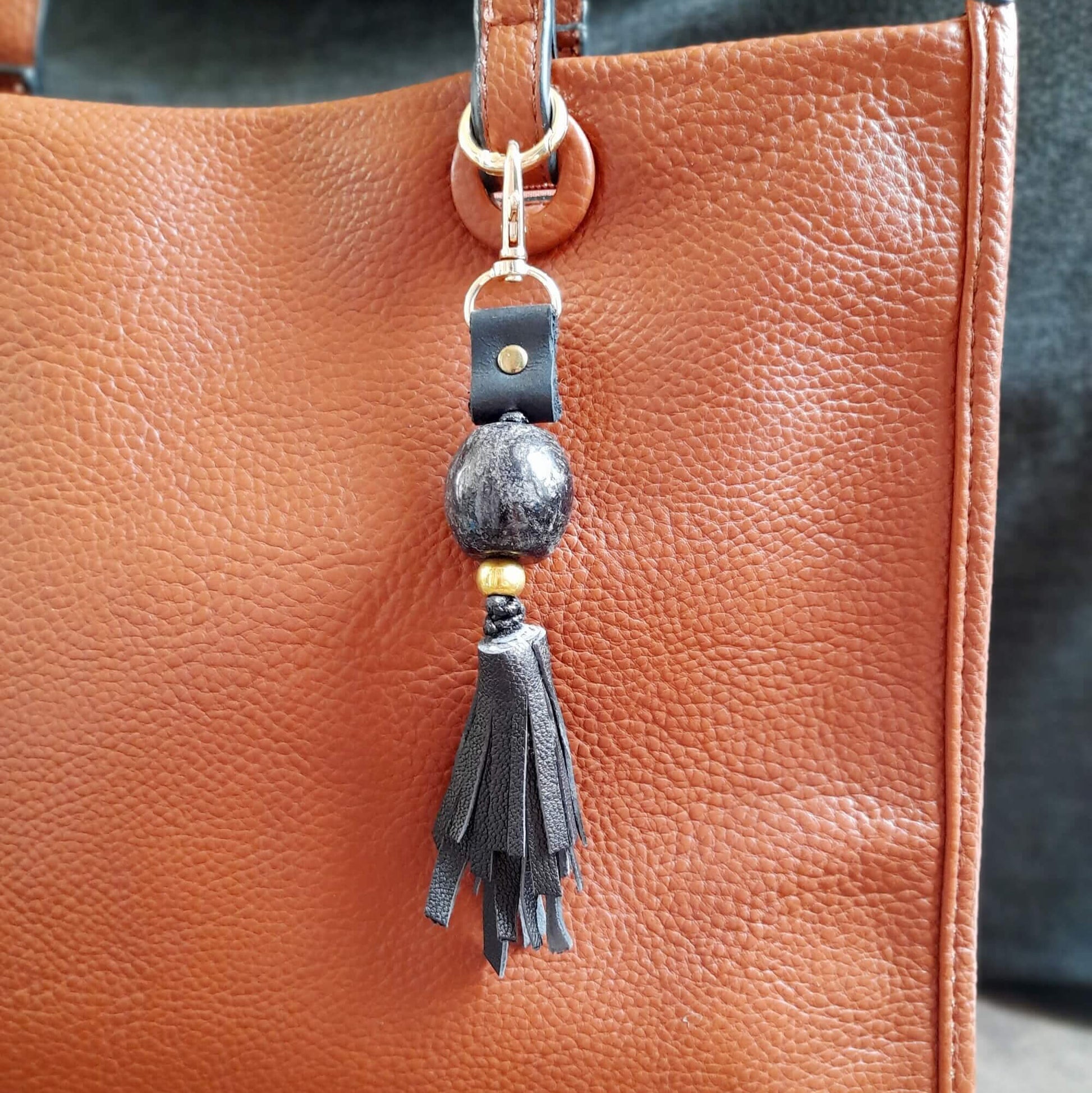 Brown leather handbag with the black keychain featuring black beads and a black tassel.