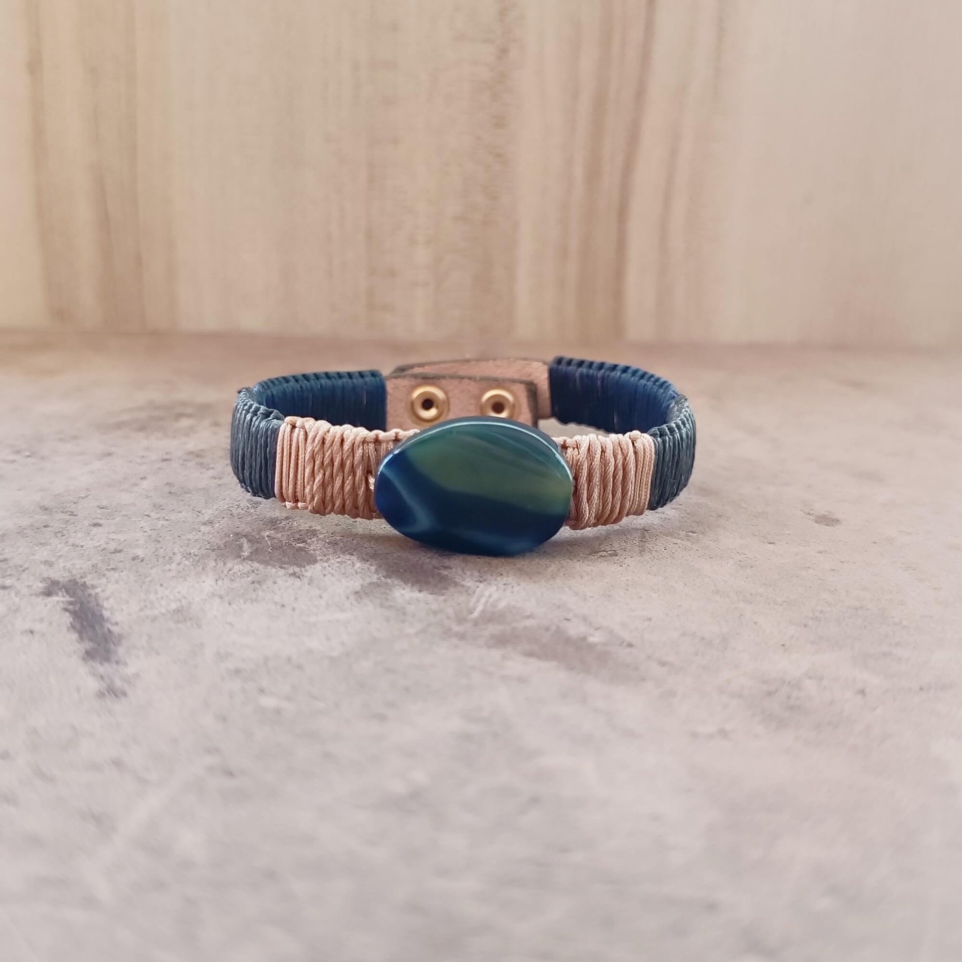 Bracelet with blue agate stone and braided design on a textured surface