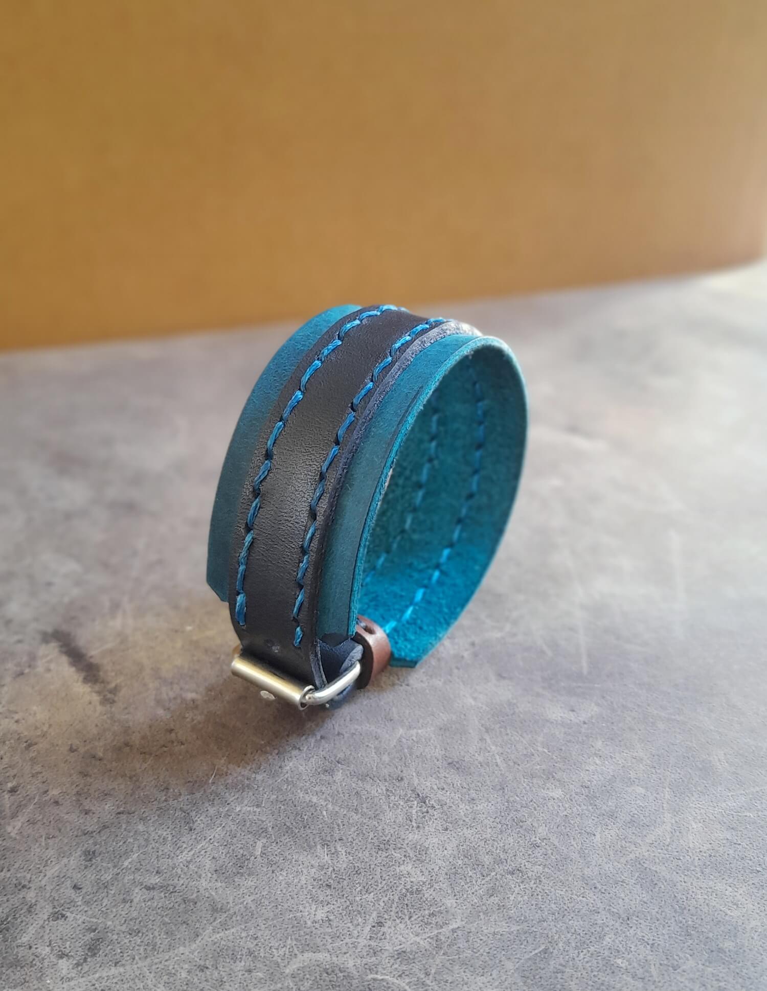Blue leather bracelet with a metal clasp on a textured surface