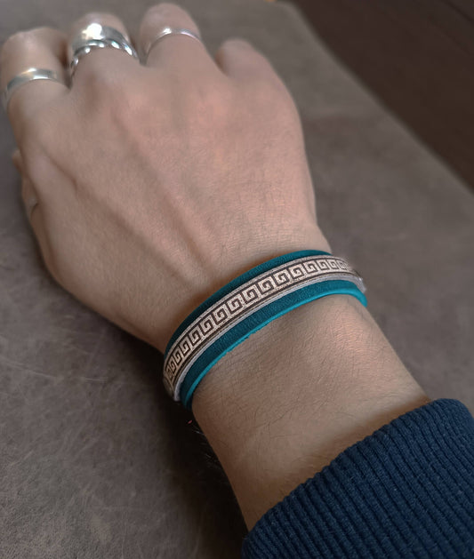 Hand wearing a blue bracelet with a pattern on a textured surface