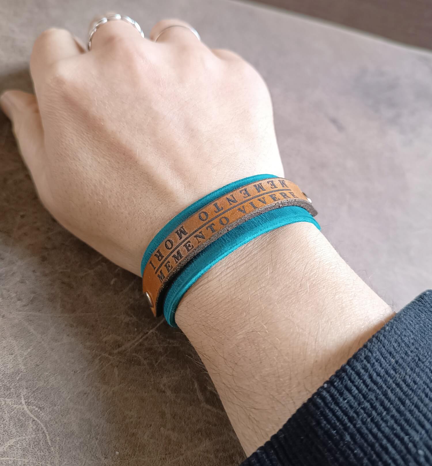 Hand wearing a blue bracelet with text on a textured surface
