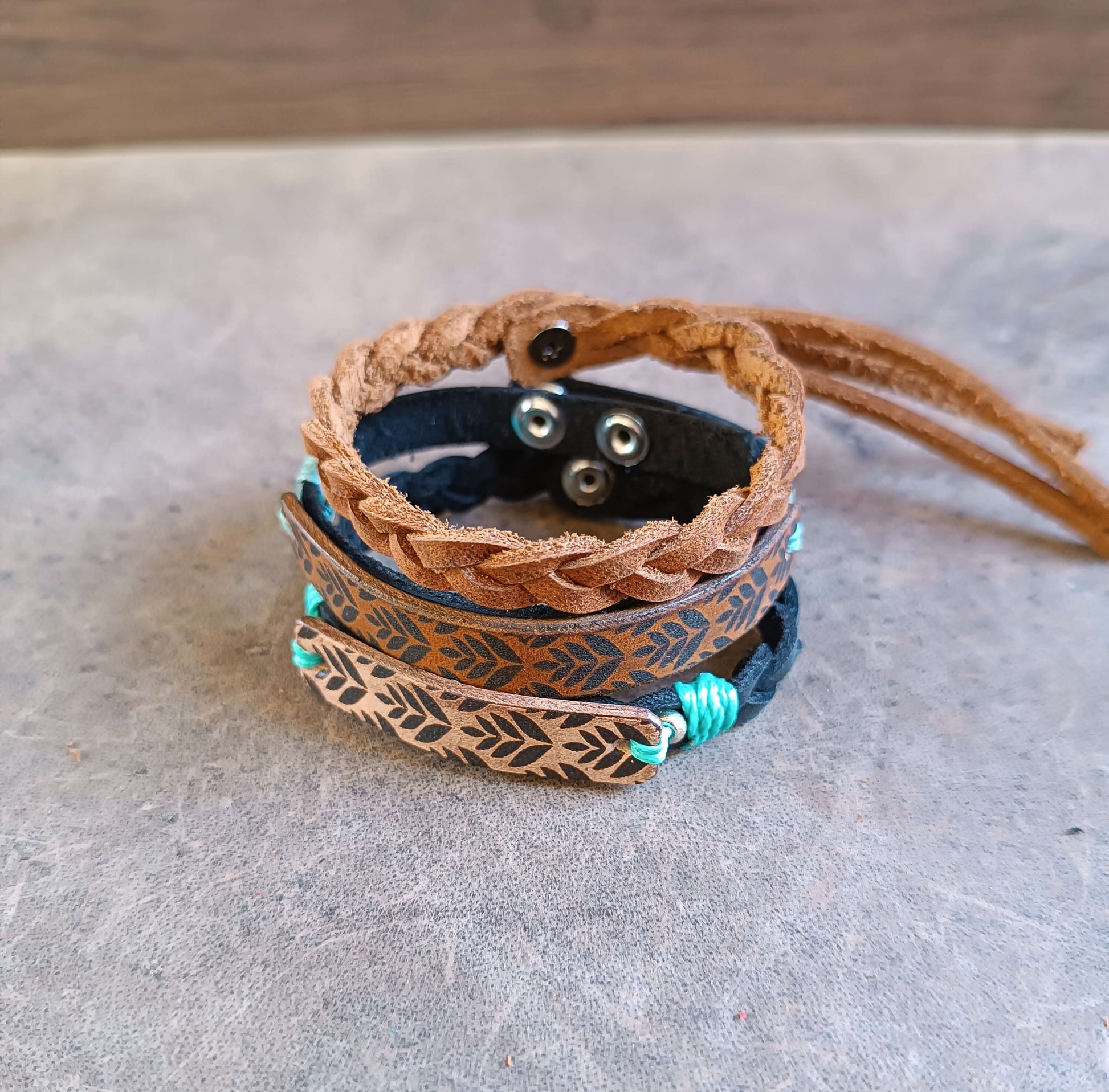 Stack of leather bracelets with braided design on a textured surface