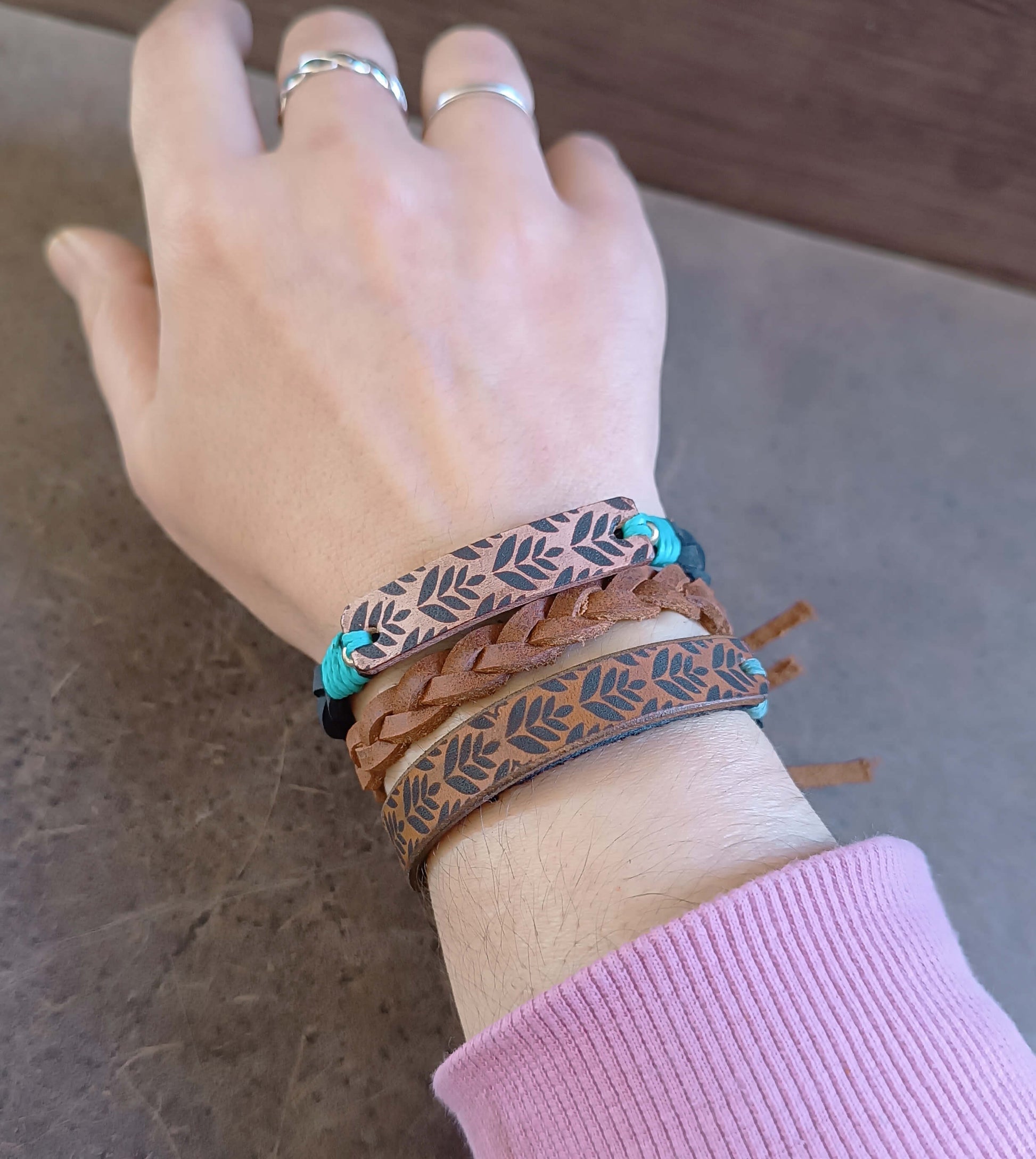 Hand wearing multiple bracelets on a neutral background