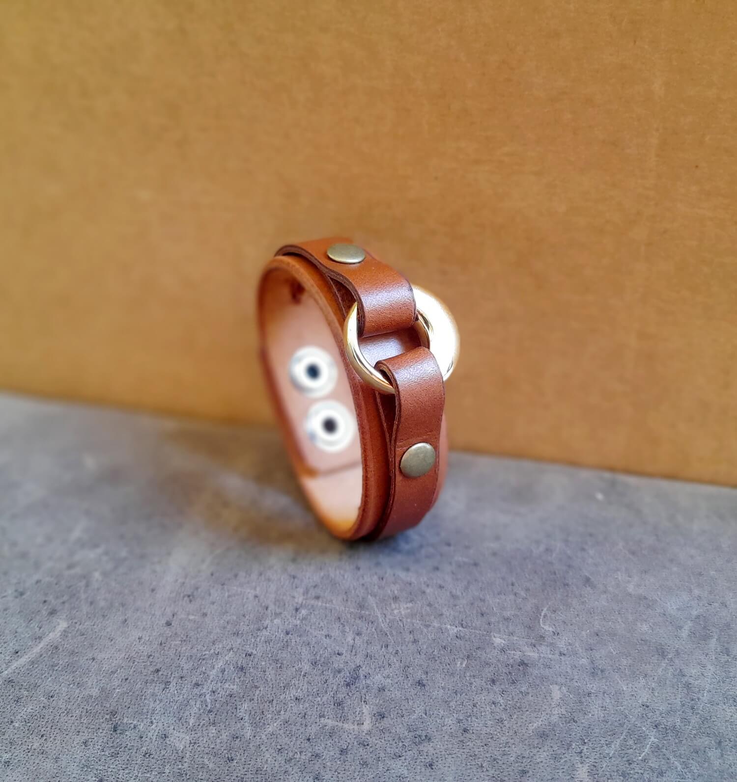 Detailed close-up of the gold stainless steel urn on the brown bracelet, highlighting its sleek design.