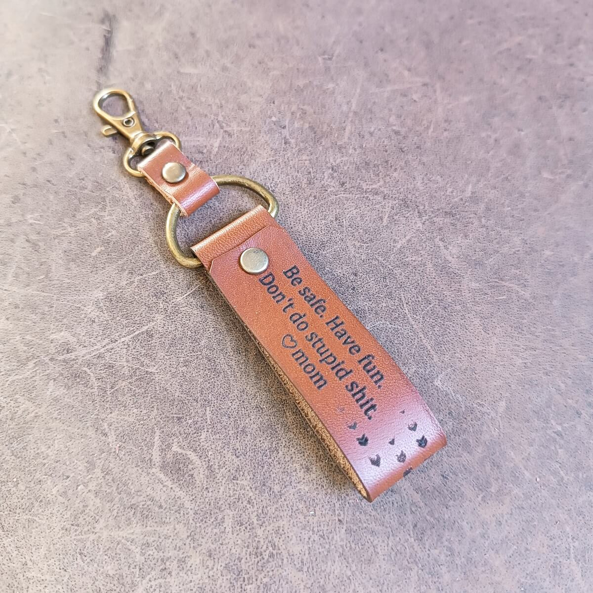 Leather keychain with engraved text on a gray surface