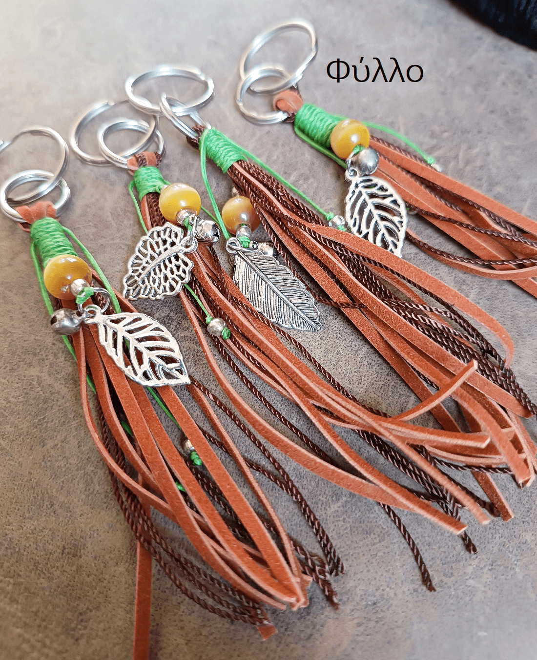 Keychains with leather tassels and leaf-shaped charms on a textured surface