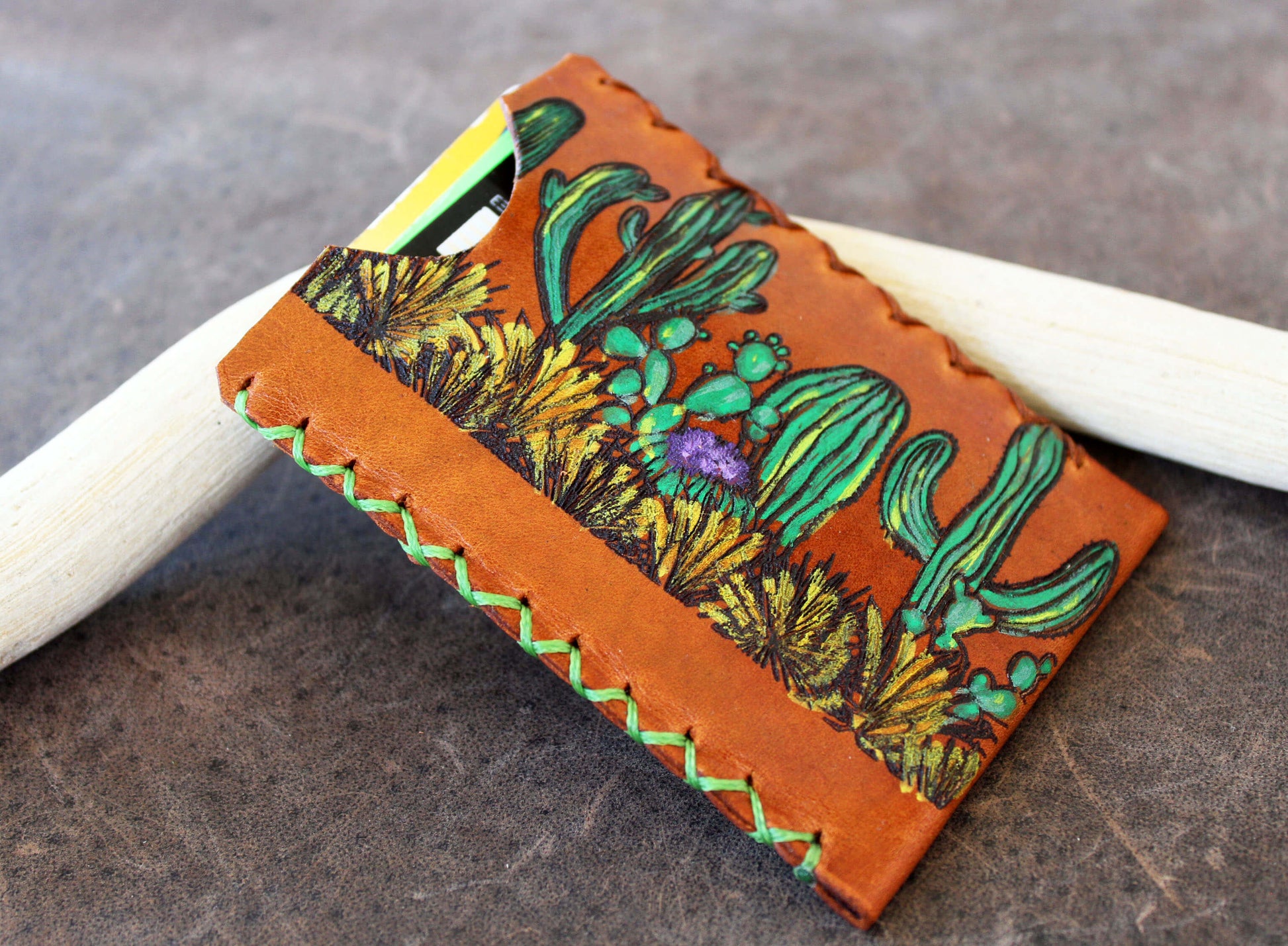 Leather cardholder with cactus design on a wooden surface