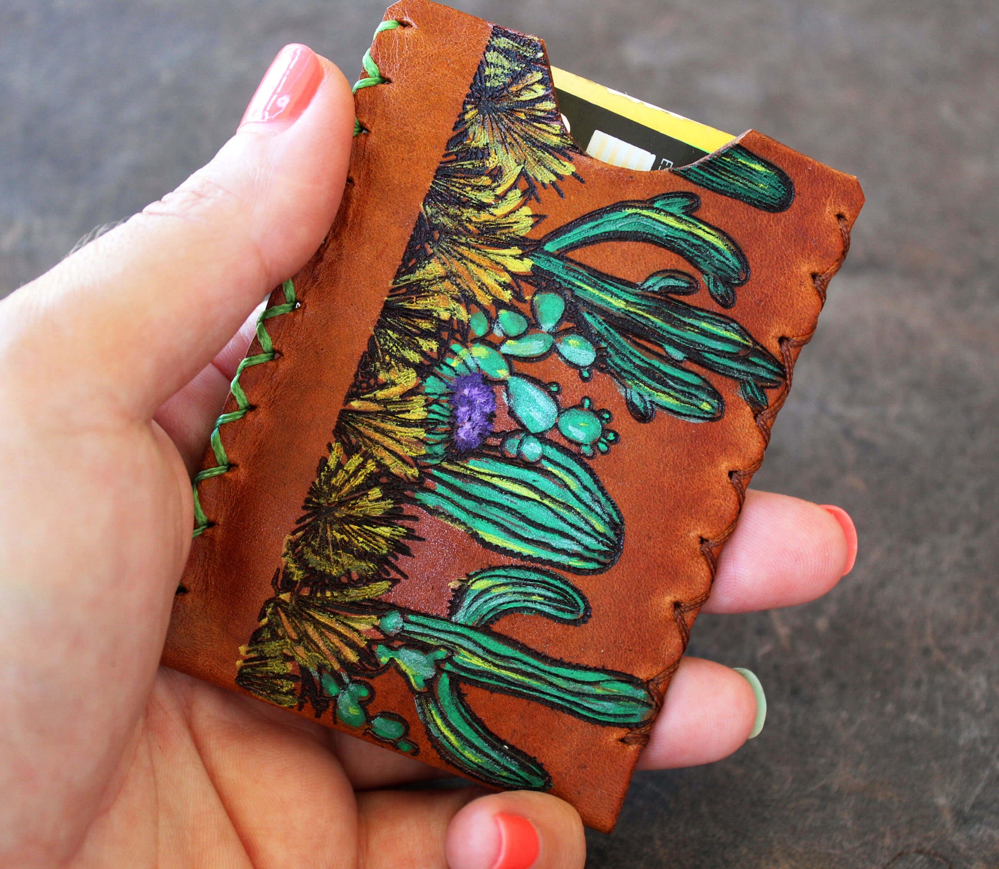 Hand holding a leather cardholder with floral design