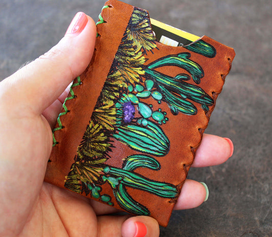 Hand holding a leather cardholder with floral design
