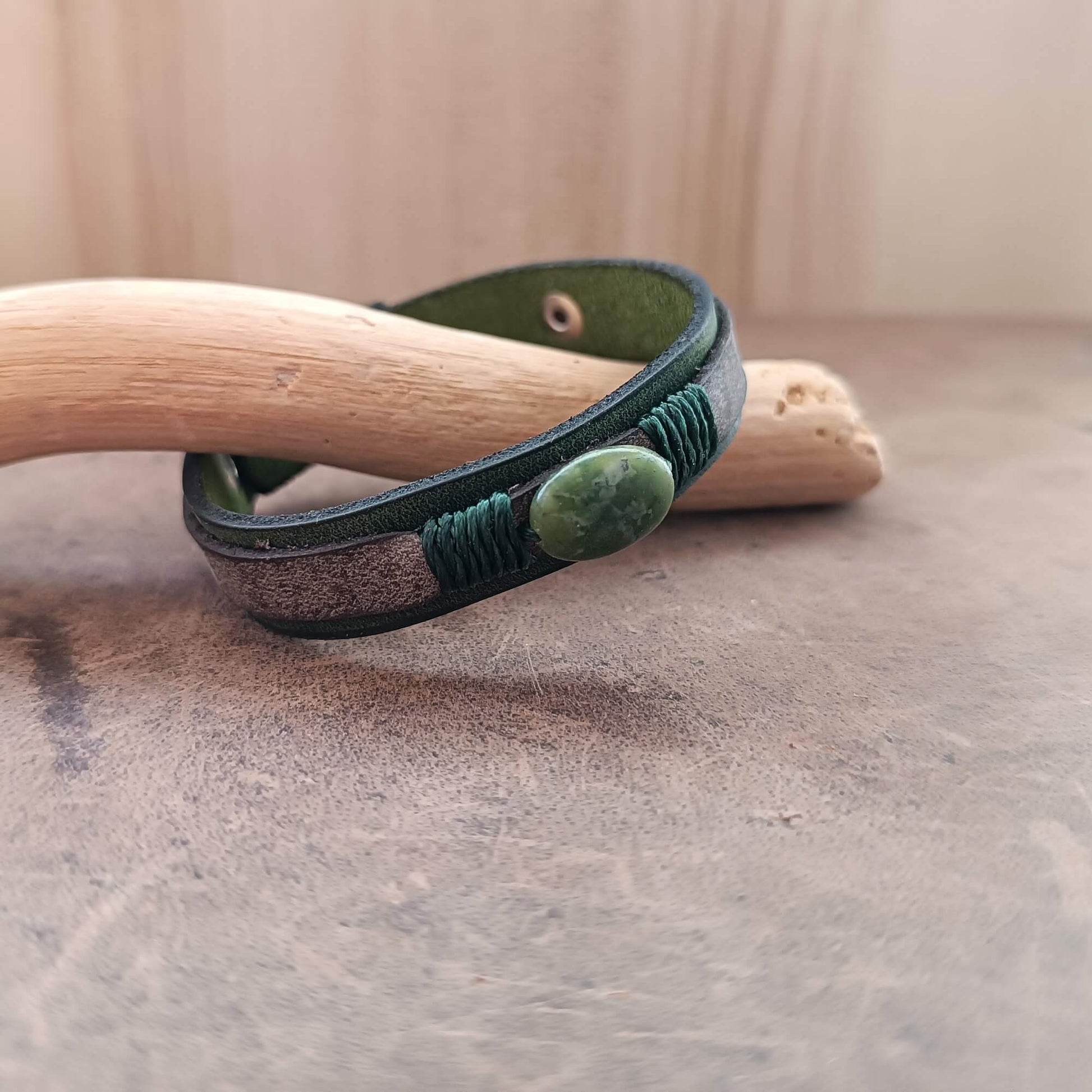 Green leather bracelet with a stone on a wooden surface