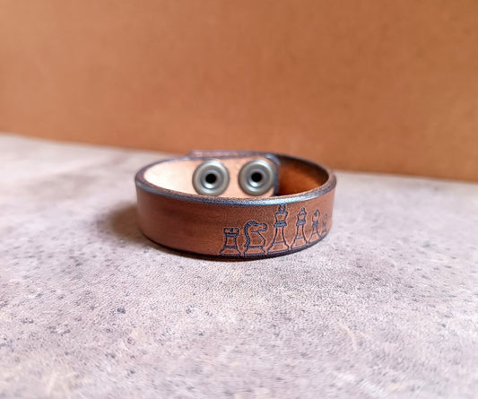 Brown leather bracelet with engraved design on a textured surface