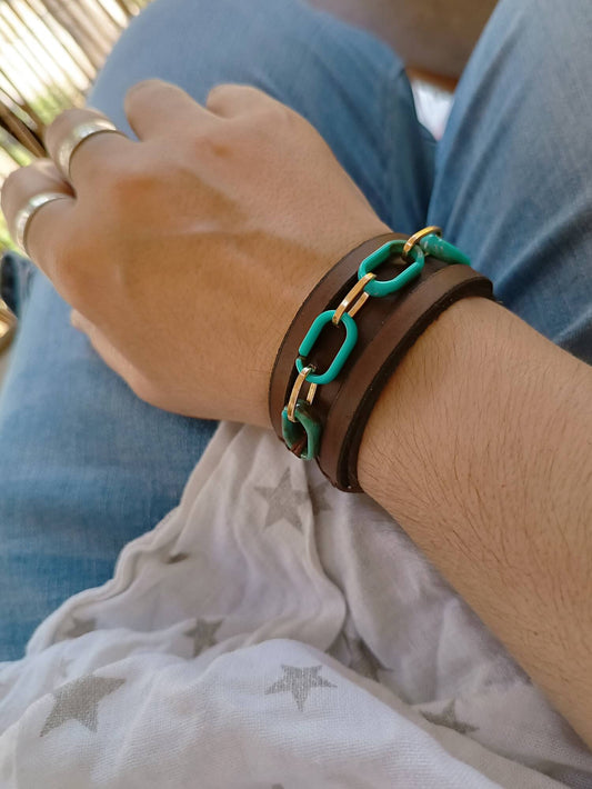 Close-up of a wrist wearing a bracelet with turquoise and gold chain links.