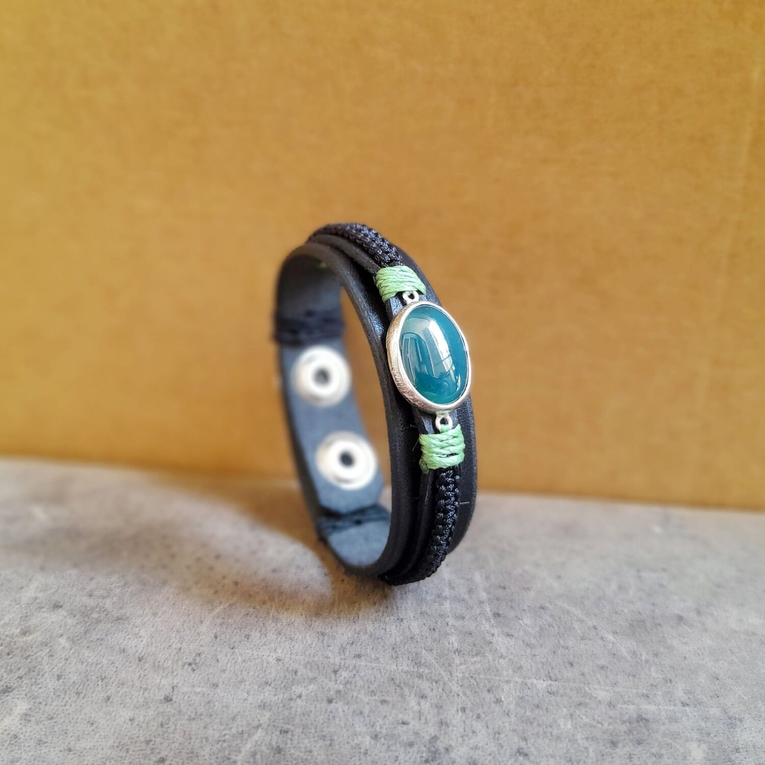 Close-up showing the black oiled full-grain Vachetta leather base, the intricate black macramé work, and the subtle green beeswax thread accent on the bracelet.