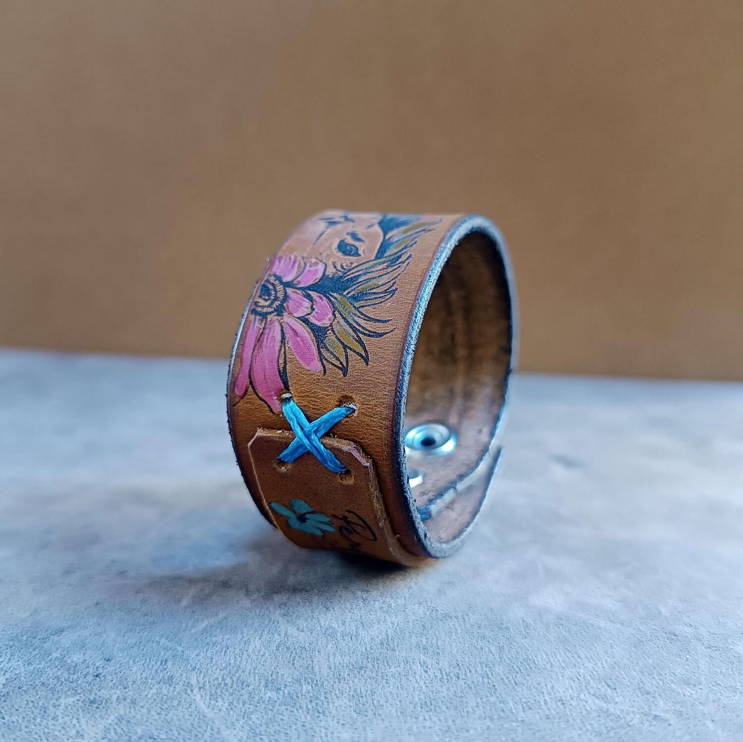 floral lioness cuff close up view, showcasing flowers and blue X stitches