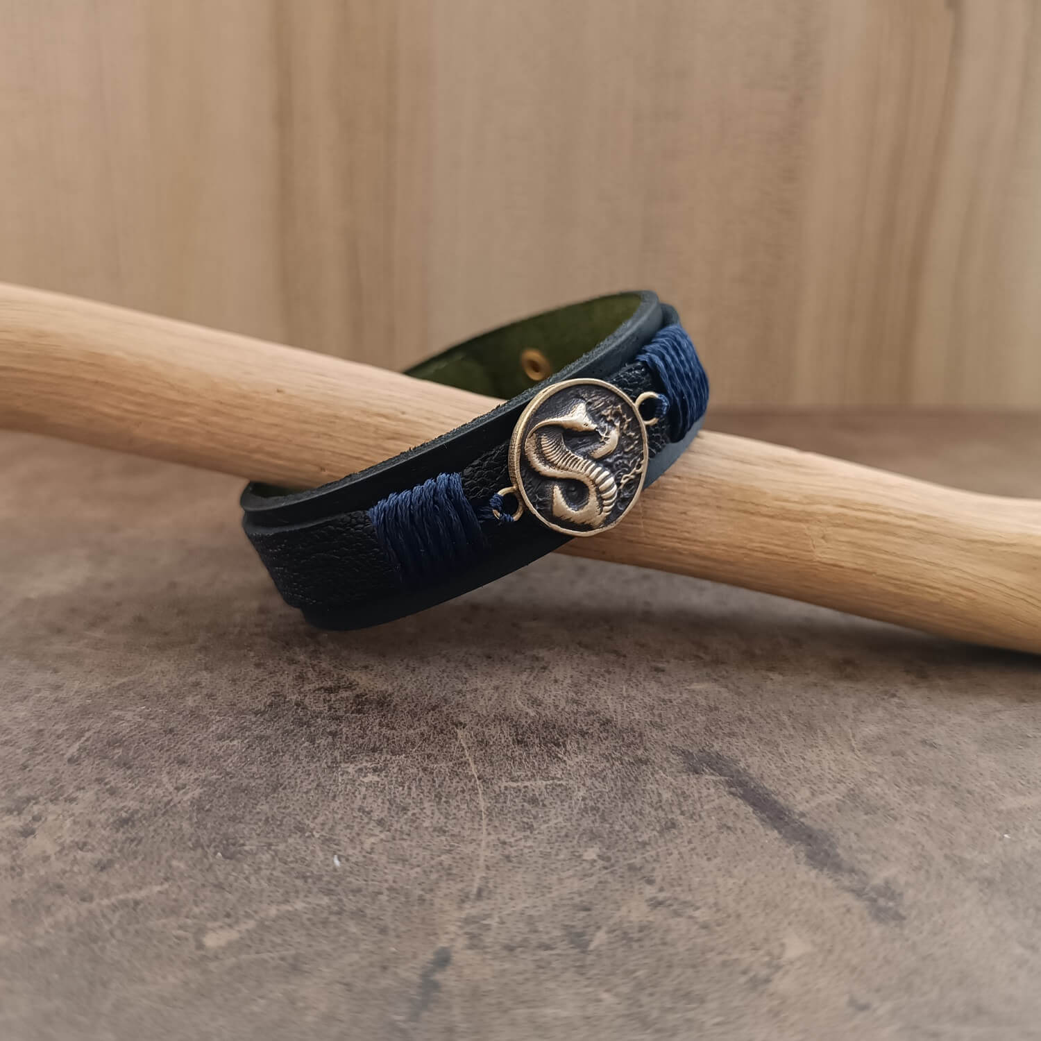 Side angle of the handmade Vincenzo Cobra Edition leather bracelet highlighting the layered texture of crackled black leather over the matte base. The antique bronze snap closure with its distinctive click is visible, sealing the vow of shadow and flame carried by the wearer.