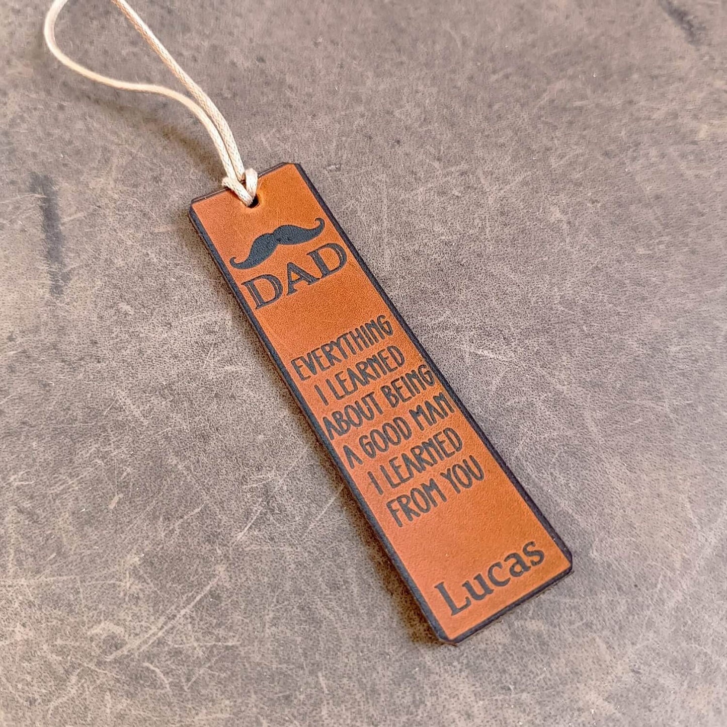 Leather bookmark for dad with engraved text on a textured surface
