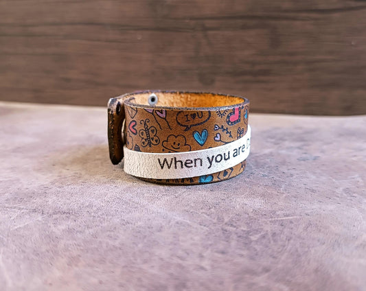 Leather bracelet with text and patterns on a wooden surface