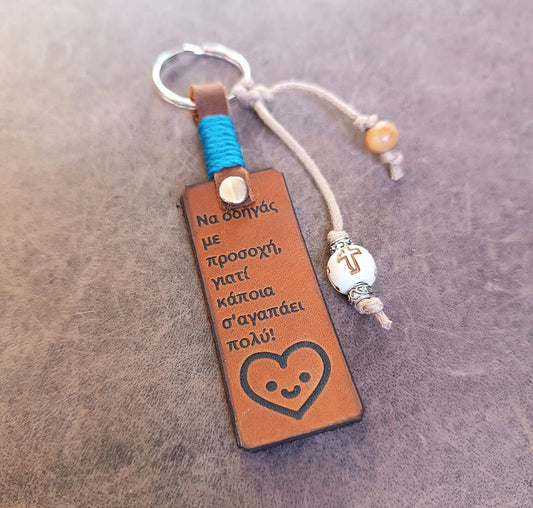 Leather keychain with engraved text and heart design on a textured surface