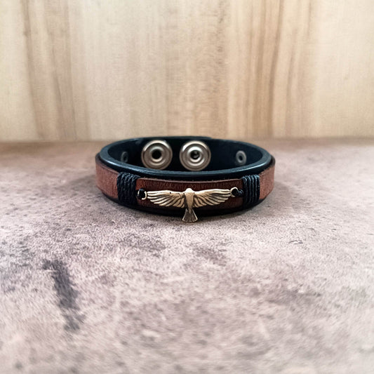 Leather bracelet with metal eagle charm on a textured surface
