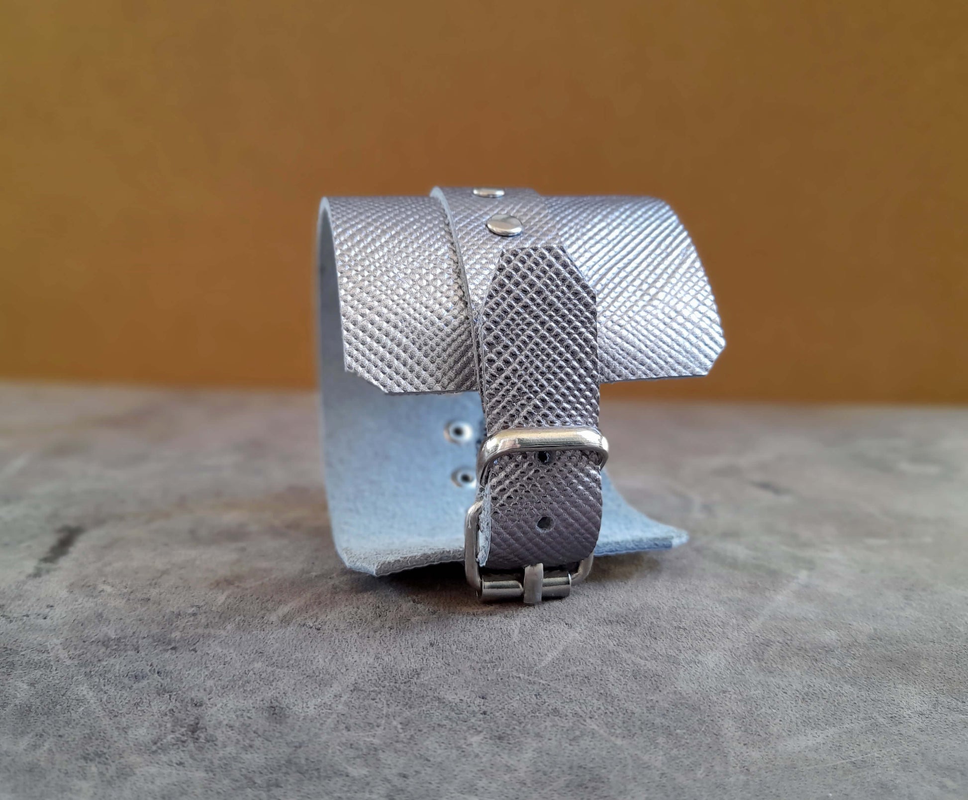 Silver textured bracelet on a textured surface with a blurred background