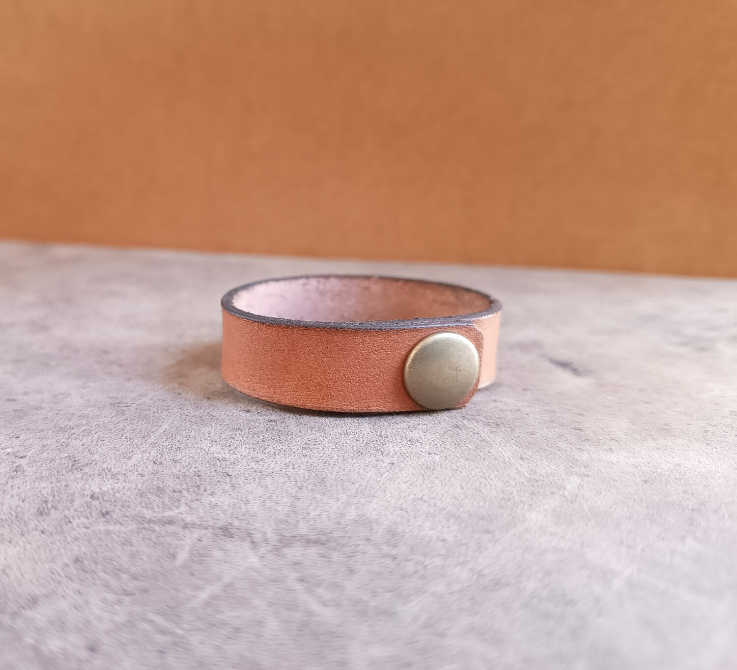 Leather bracelet with a button clasp on a textured surface