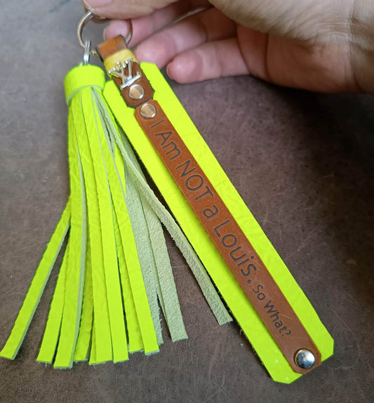 Keychain with tassels and engraved text on a brown surface