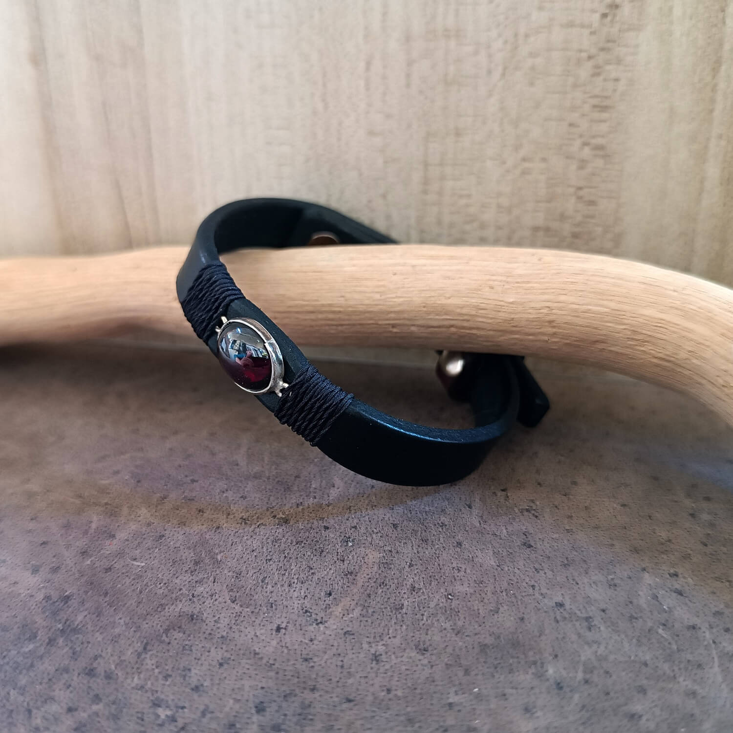 Black bracelet with a red garnet on a wooden surface