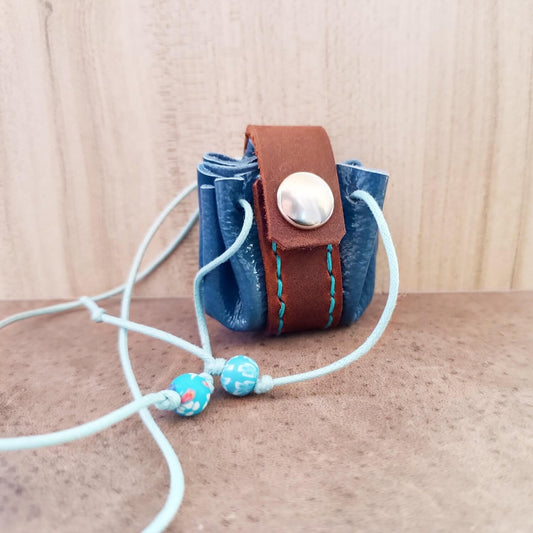 Glossy Blue and brown leather neck pouch with a snap button closure, light blue cotton cord and decorative blue floral fimo beads