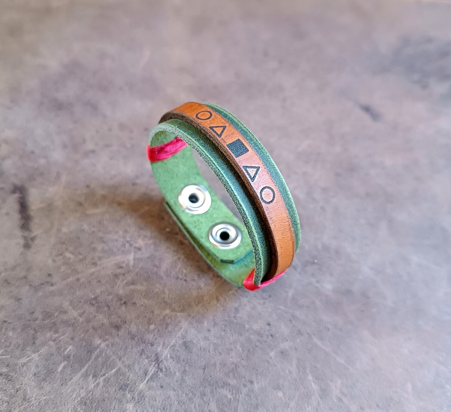 Green bracelet with geometric patterns on a metallic surface