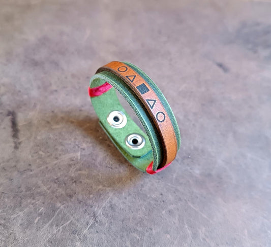 Green bracelet with geometric patterns on a metallic surface