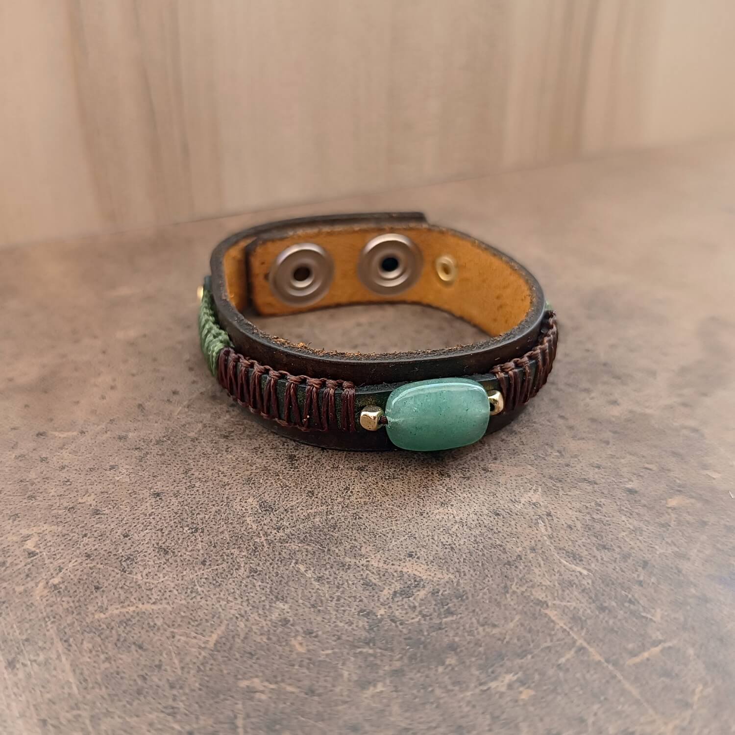 the green aventurine leather cuff on leather surface