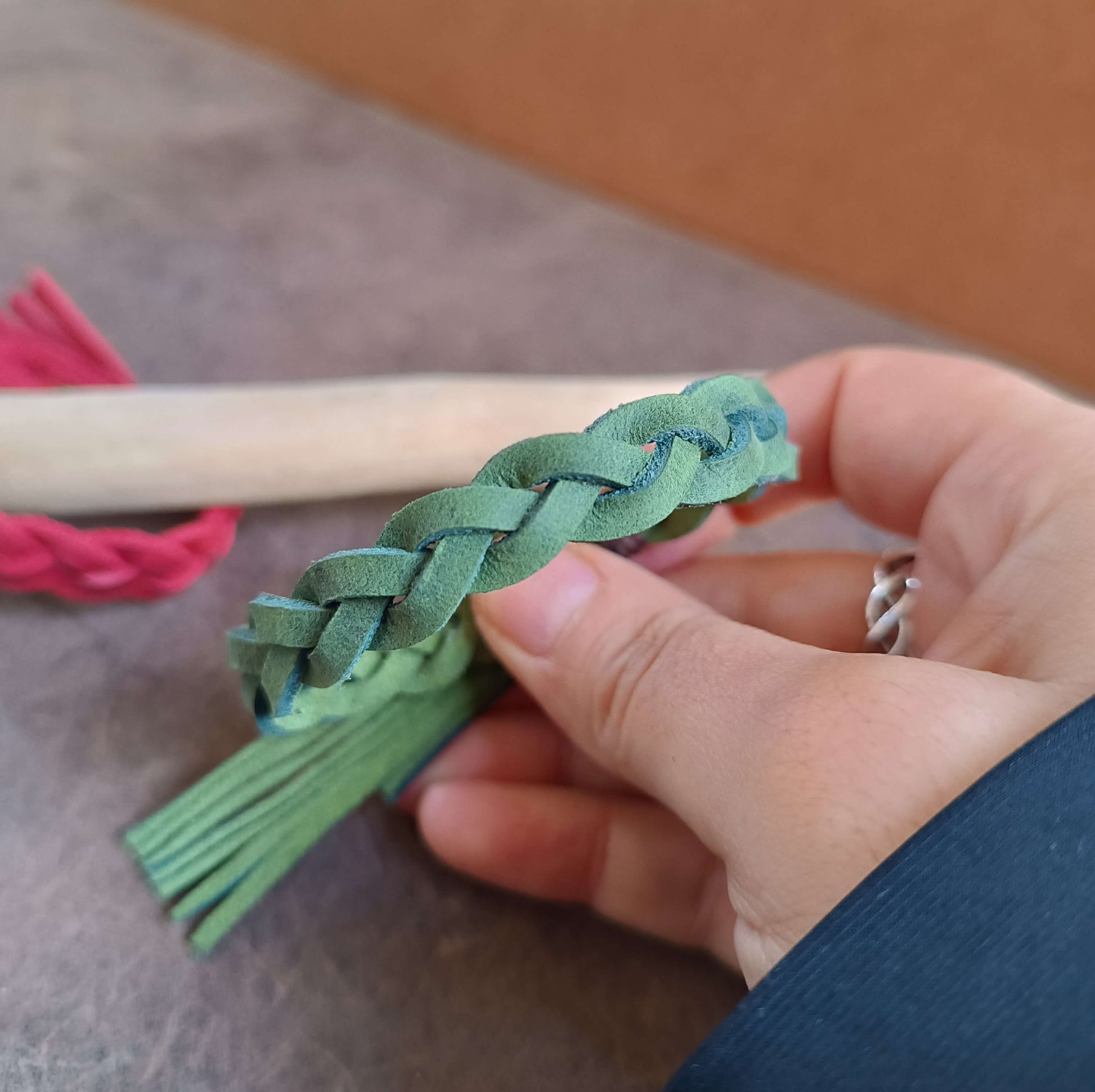 Hand holding a braided green leather bracelet