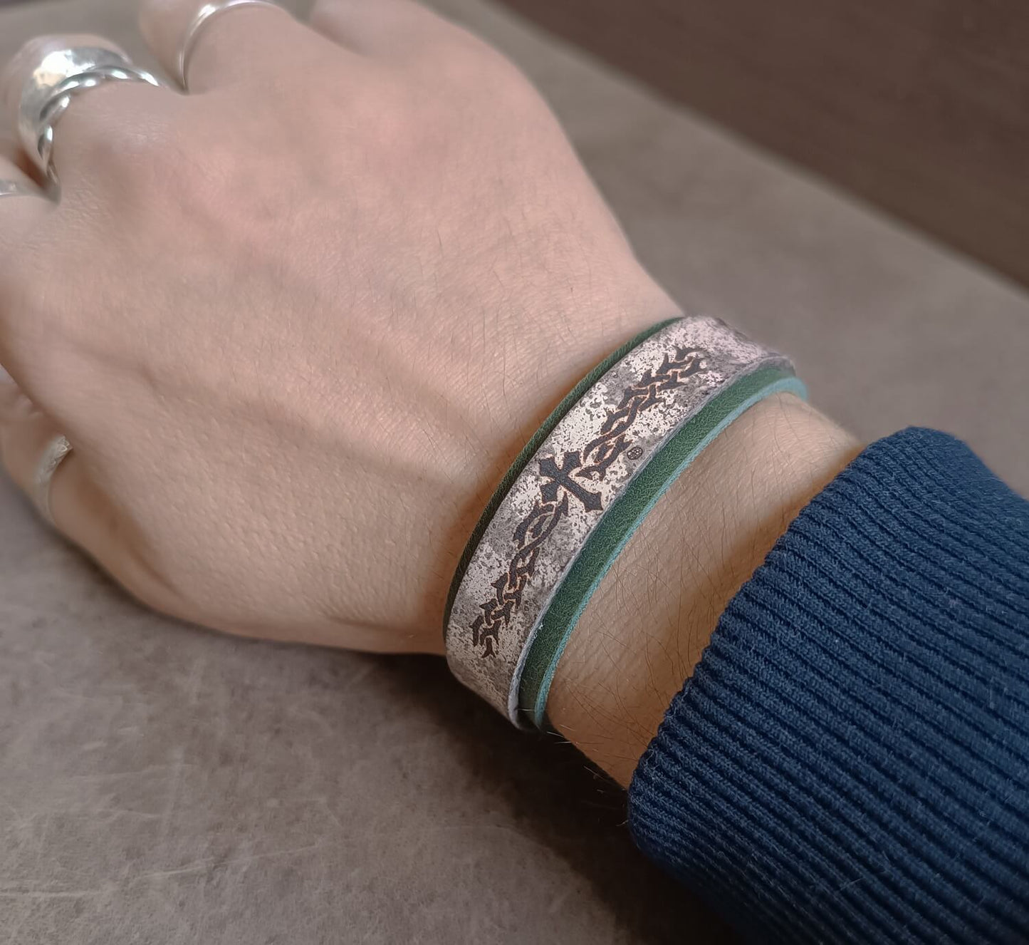 Hand wearing a bracelet with intricate design on a neutral background