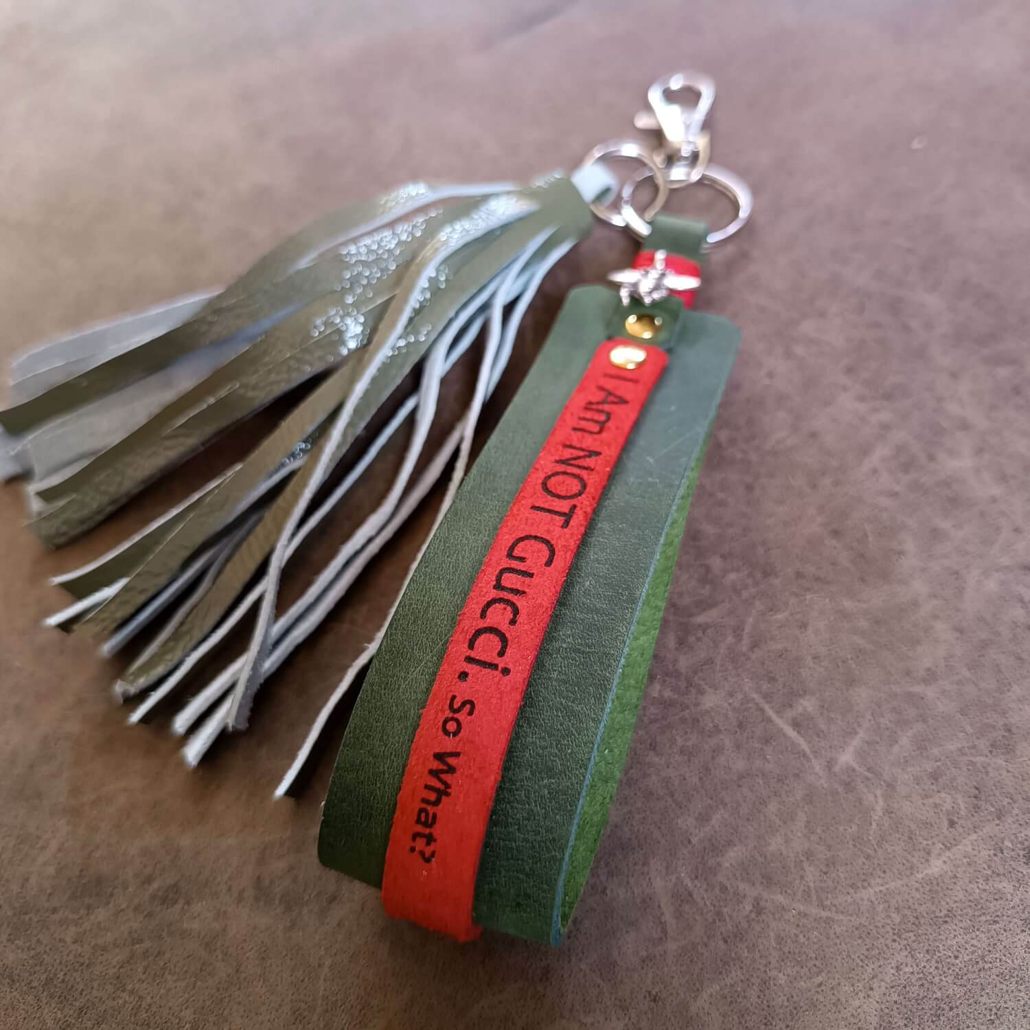 Green tassel keychain with red tag on a brown surface