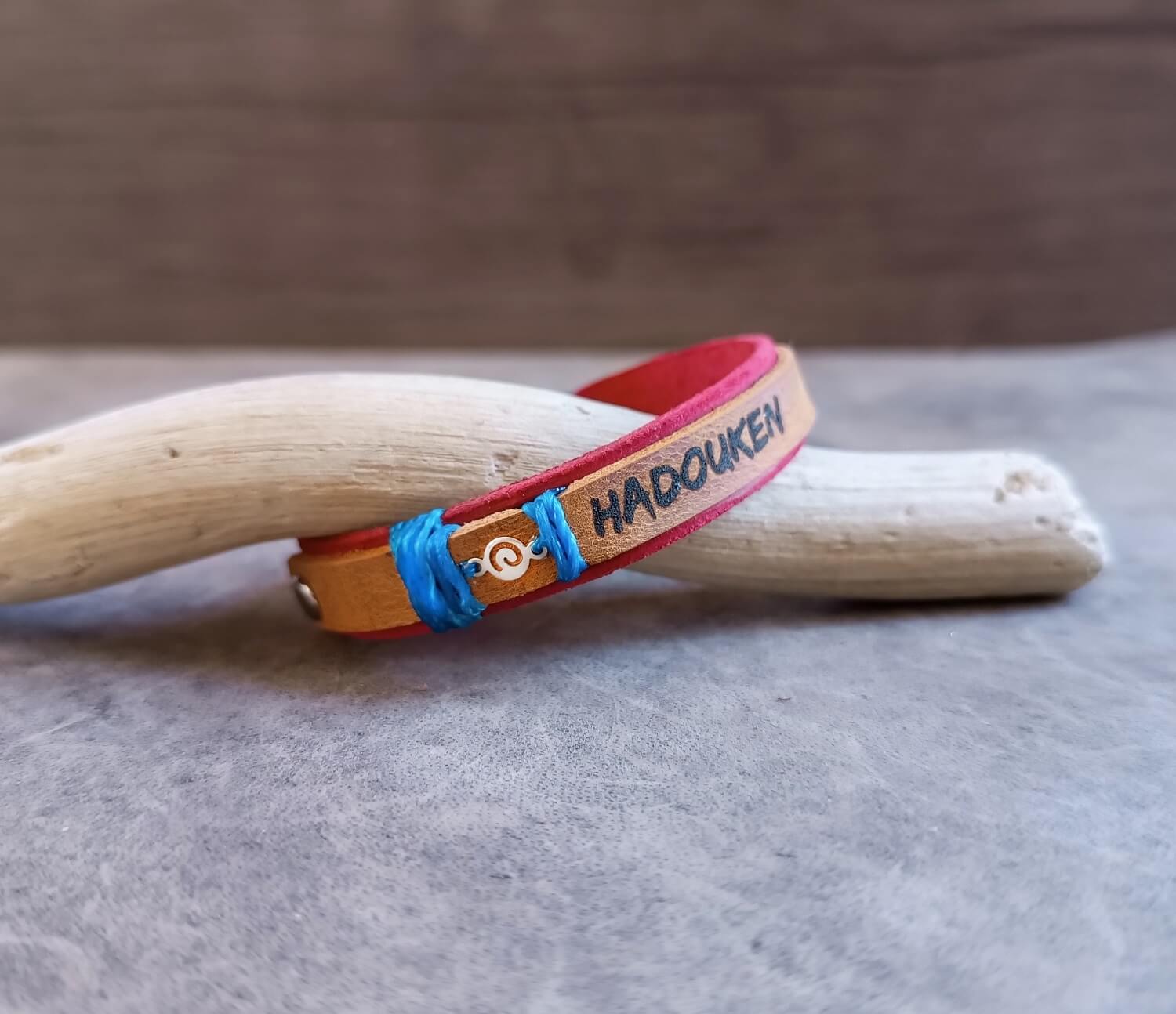 Bracelet with 'HADOUKEN!' engraving on a wooden stick against a neutral background