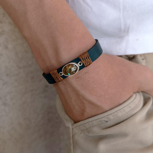 Close-up of a wrist wearing a bracelet with a natural stone on a neutral background