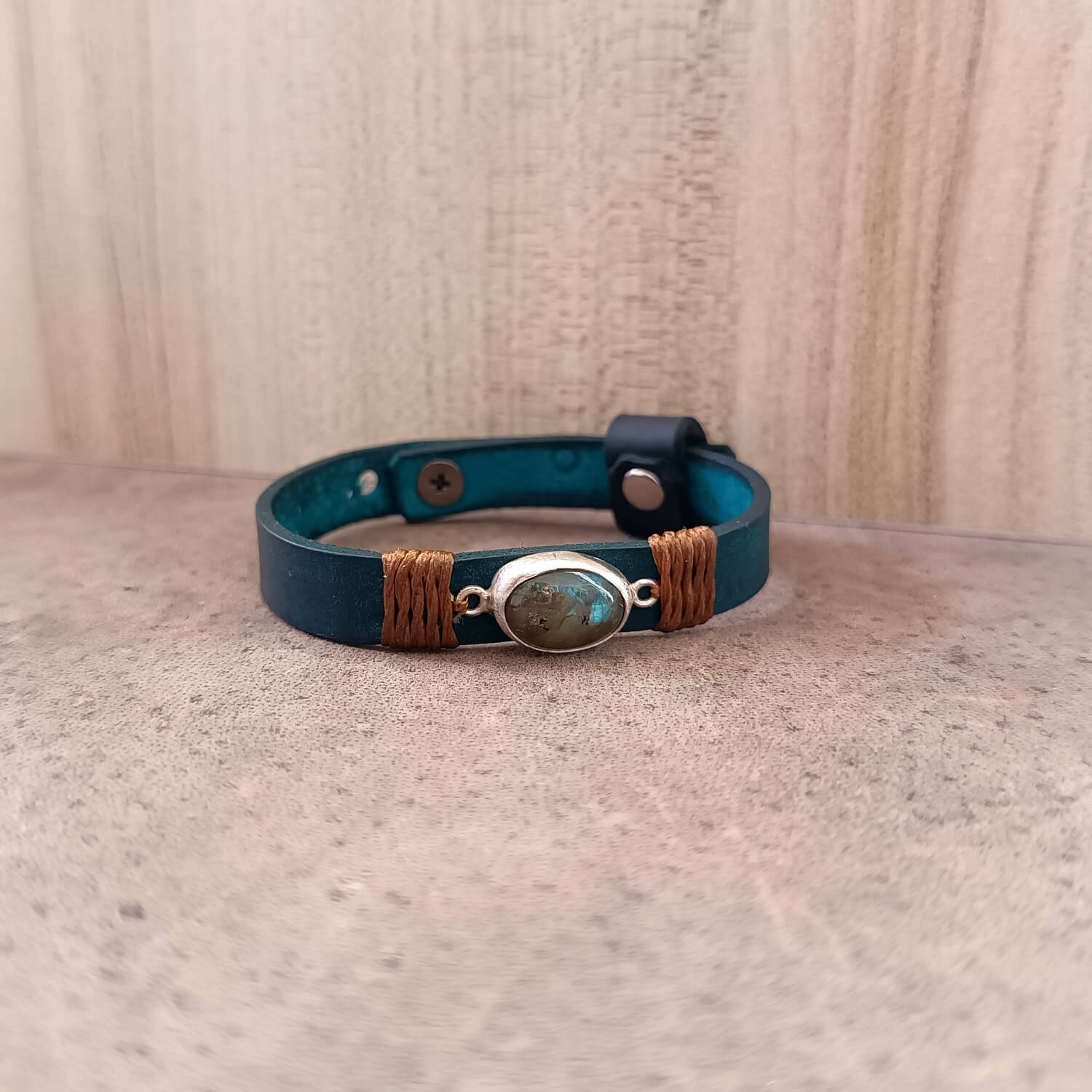 Blue leather bracelet with a central stone on a textured surface